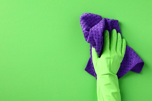 Main nettoyant un mur avec un chiffon microfibre 