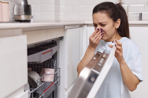 Pourquoi mon lave vaisselle sent mauvais ? Femme se pinçant le nez après avoir ouvert son lave vaisselle